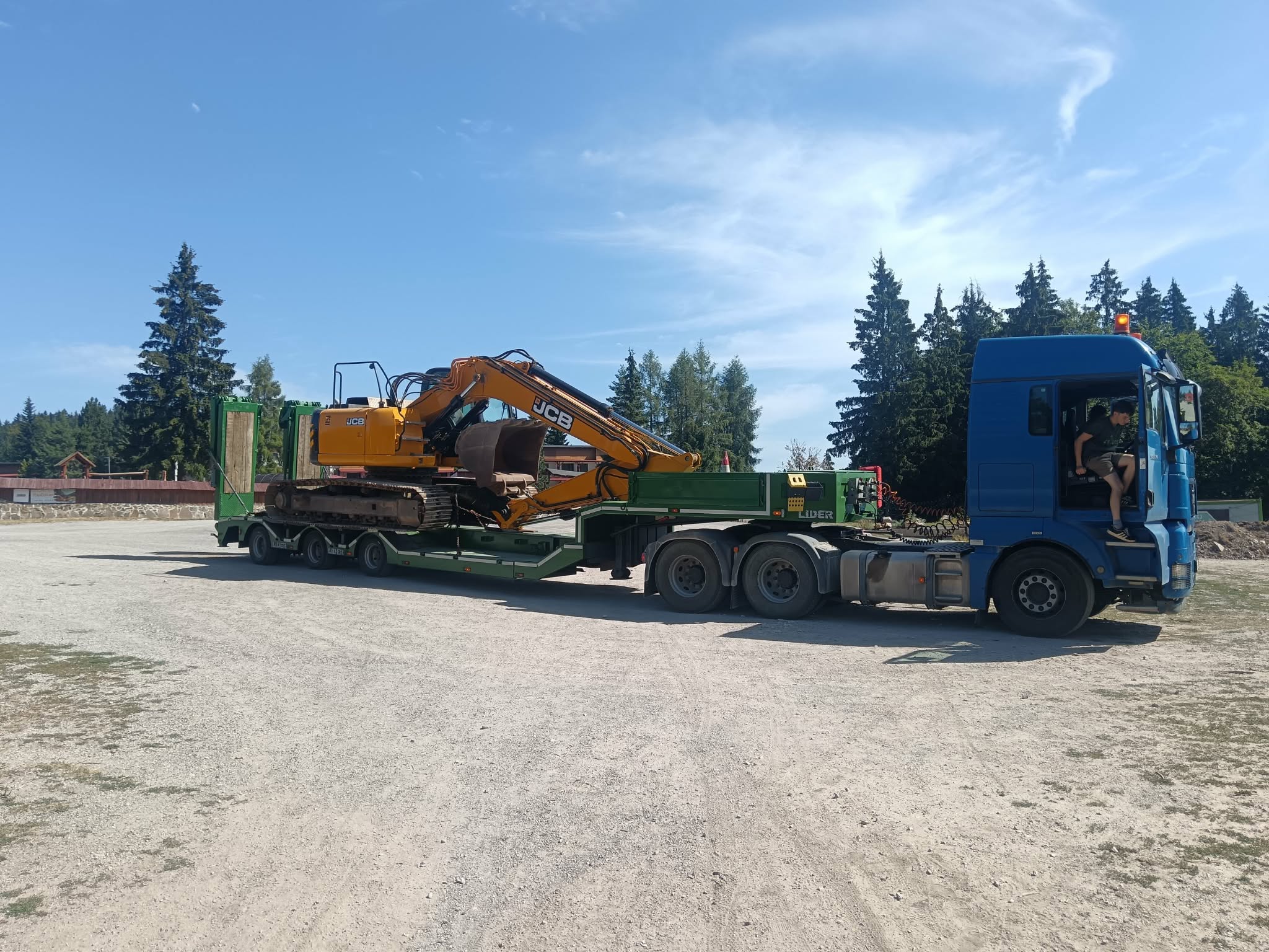 JCB báger naložený na podvalník, cesta na zákazku
